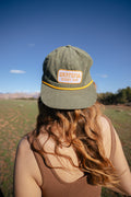 Woman wearing Grateful Every Day Trek Light corduroy snapback hat, enjoying nature with a green field background.