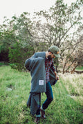 Man outdoors holding the Greyson Blanket in a green field, showcasing its sleek and modern design.