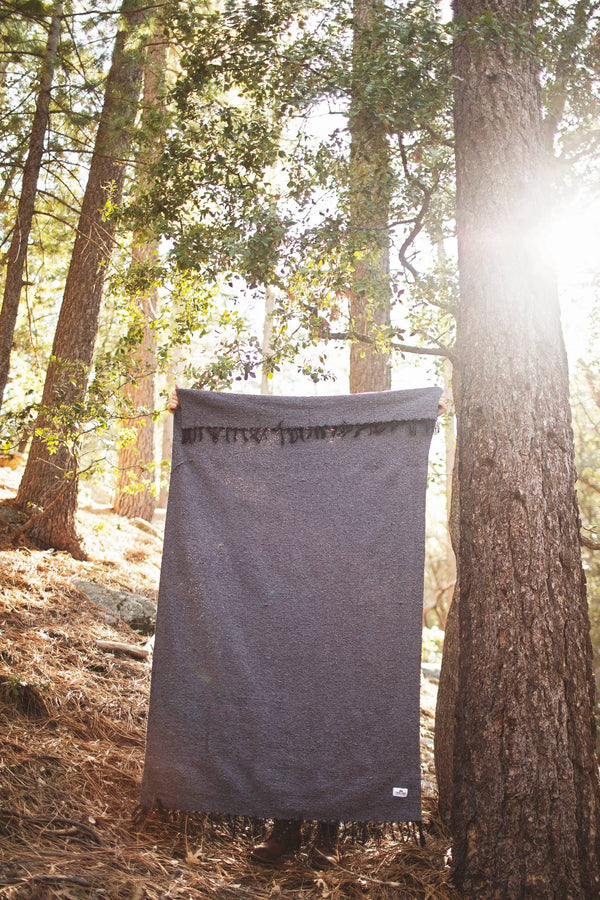 Greyson Blanket displayed outdoors, showcasing its sleek design and soft, cuddly texture against a natural backdrop.