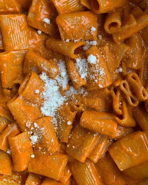 Creamy rigatoni pasta with rich tomato sauce and grated cheese on top.