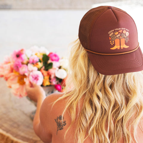 Woman wearing a Grow Your Own Way Hat, stylishly designed with floral graphics and adjustable fit.