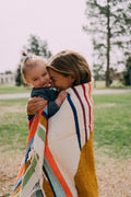 Mother and child wrapped in a colorful blanket, enjoying time outdoors with the Halley's Comet Blanket.