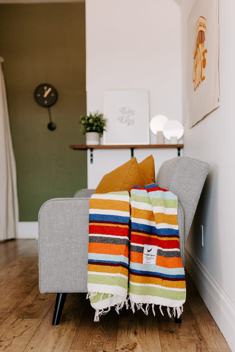 Cozy living room with a colorful striped blanket from Trek Light, adding vibrant style to a modern sofa.