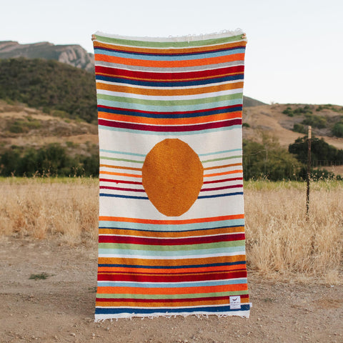 Trek Light's vibrant Halley's Comet Blanket, handwoven with recycled materials, displayed in a scenic outdoor setting. Cozy and eco-friendly.