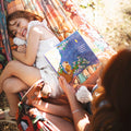 A joyful child reading a book while relaxing with a parent in a Double Hammock & Pro Hanging Straps (Midnight Mushroom Print).