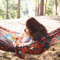 Woman and child enjoying a book in a Double Hammock & Pro Hanging Straps (Midnight Mushroom Print) in the woods.