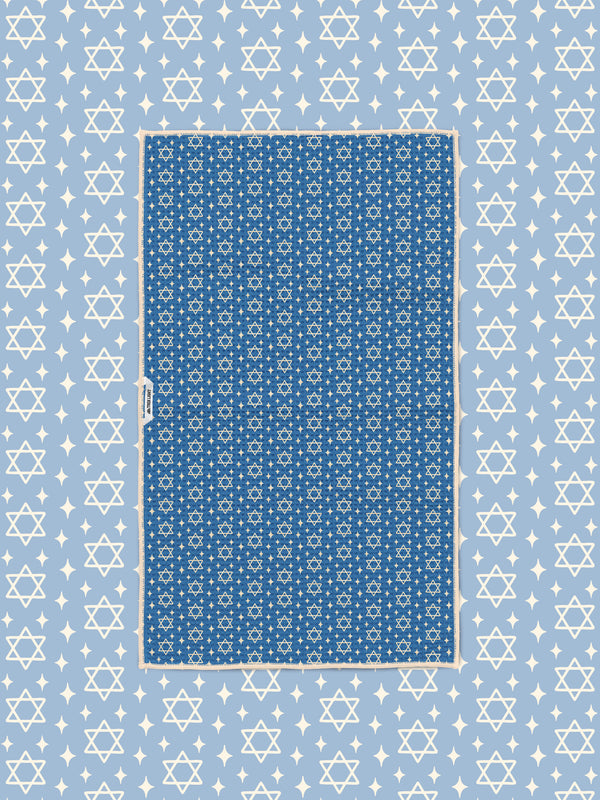 Blue Star of David kitchen towel styled flat on matching light blue star-print background