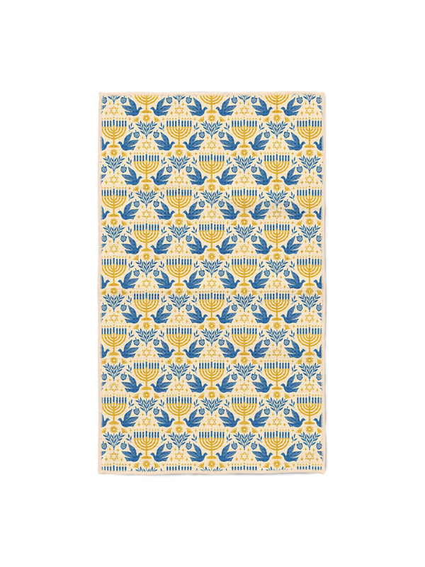Cream kitchen towel with blue and gold menorahs, doves, and Star of David folk pattern for festive kitchens