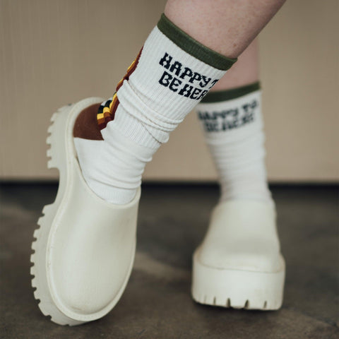 Cozy Trek Light 'Happy To Be Here' socks paired with chunky shoes, offering perfect comfort and style for any adventure.