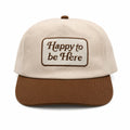 Happy To Be Here Hat featuring beige fabric with brown visor and embroidered lettering.