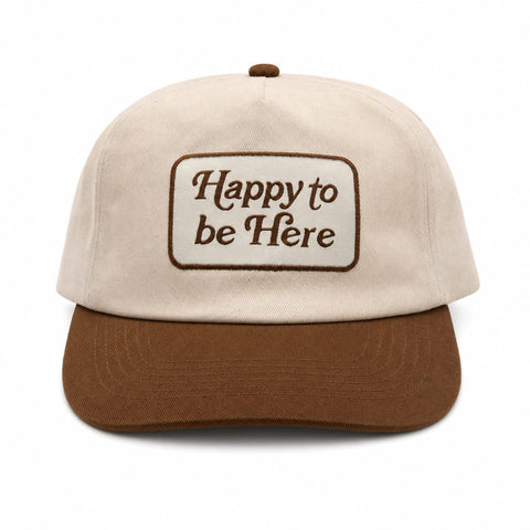 Happy To Be Here Hat featuring beige fabric with brown visor and embroidered lettering.