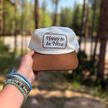 Happy To Be Here Hat held in hand, featuring a brown brim and comfortable design, perfect for all-day wear.