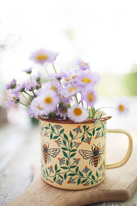 Honey Bee Enamel Mug 16oz filled with purple flowers, featuring a beautiful honey bee design.