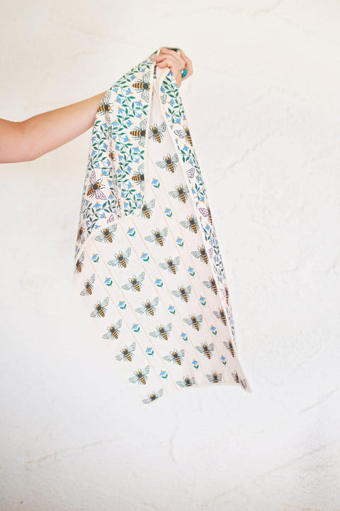 Honey Bee Kitchen & Tea Towel held up, showcasing vibrant bee patterns on eco-friendly fabric.