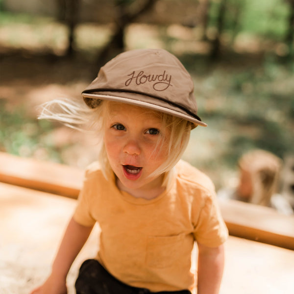 Child wearing the Howdy Kids Hat, smiling in a sunny outdoor setting with a playful vibe.