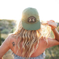 Woman wearing Howlin' At The Moon Hat against a sunset backdrop, showcasing style and comfort.