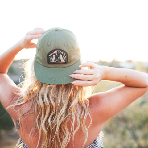 Woman wearing a Howlin' At The Moon Hat against a sunset backdrop, showcasing style and comfort.