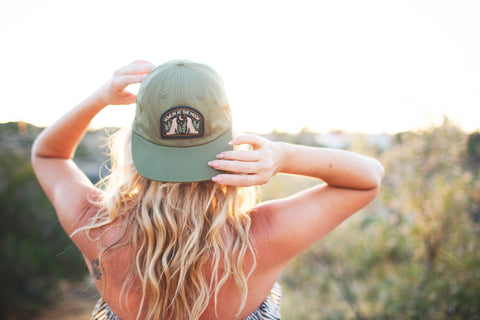 Woman wearing a Howlin' At The Moon Hat against a sunset backdrop, showcasing style and comfort.