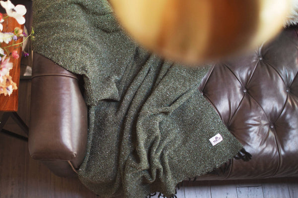 Humboldt Blanket draped on a leather couch, showcasing earthy tones and natural textures, perfect for cozy comfort.