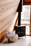 Cozy Huntington Blanket by Trek Light near a wood stove in a rustic cabin setting, perfect for beach or campfire nights.