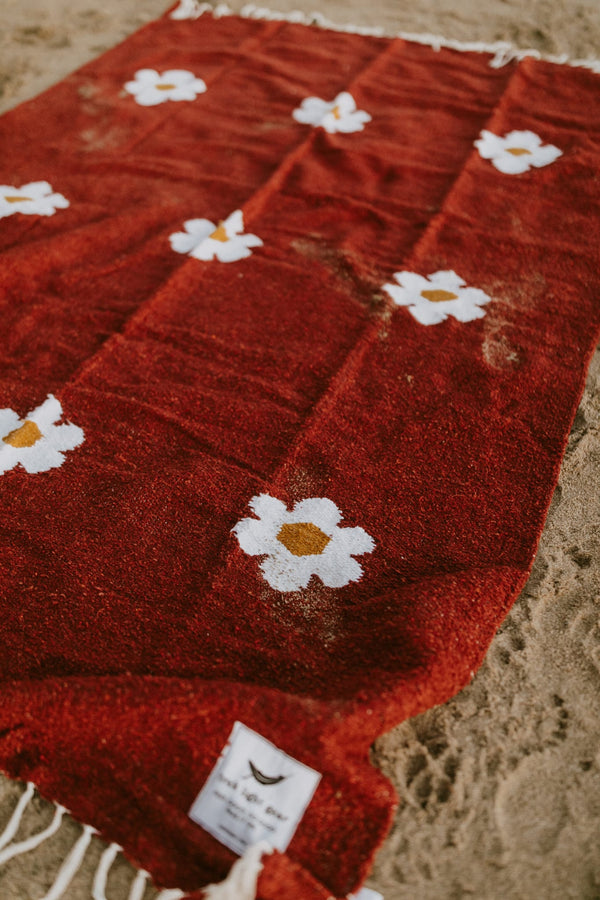 Lazy Daisy Blanket with charming daisy pattern on a red background, perfect for relaxing moments. Explore cozy with Trek Light.