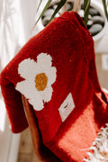 Cozy red blanket with a white daisy design draped over a chair, embodying Trek Light's Lazy Daisy vibe.