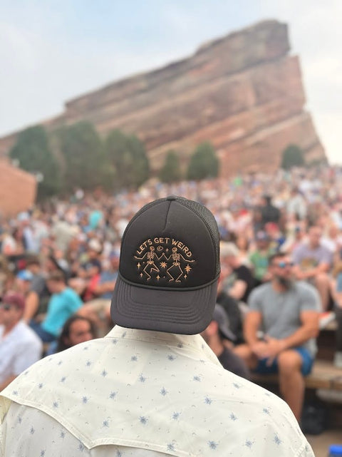 Back of a person wearing the black Let's Get Weird Hat in a crowd at Red Rocks Amphitheatre, Trek Light