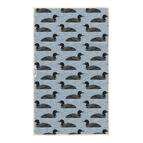 Loons dish towel featuring loon birds in black on blue water-inspired background with geometric wave patterns throughout