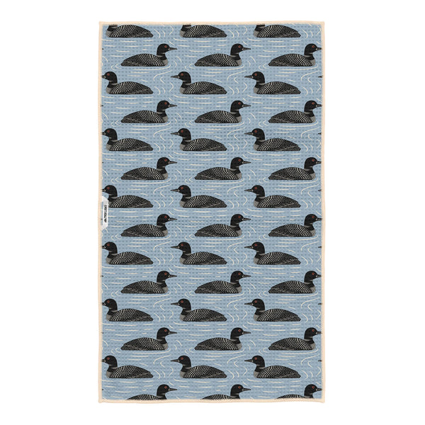 Loons dish towel featuring loon birds in black on blue water-inspired background with geometric wave patterns throughout