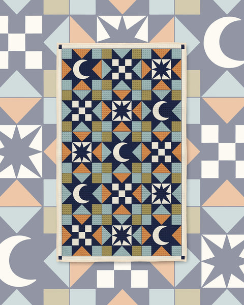 Lucky Stars Kitchen & Tea Towel with navy quilt-style geometric blocks of moons and stars in blue, peach and cream
