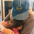 Mama Hat with heart embroidery worn by a person embracing a child, showcasing comfort and style.