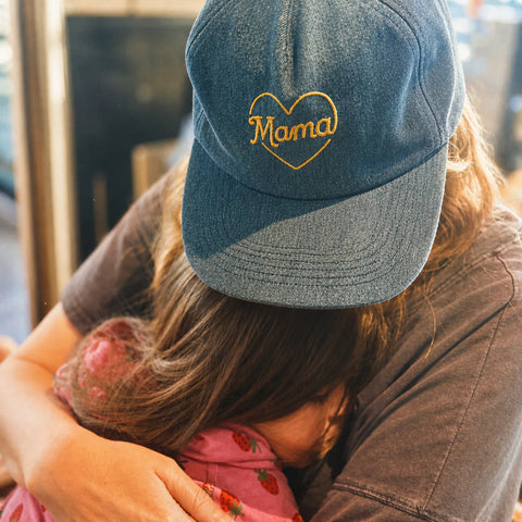 Mama Hat with heart embroidery worn by a person embracing a child, showcasing comfort and style.
