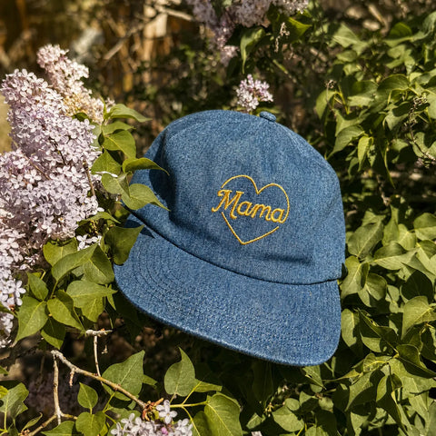 Mama Hat on a bed of lilac flowers, featuring a heart design and adjustable fit for comfort.