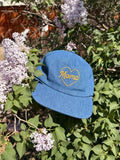 Mama Hat on a bed of lilac flowers, featuring a heart design and adjustable fit for comfort.