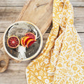 Vibrant Meadow Kitchen & Dish Towel on wooden board beside artistic deer plate adorned with orange slices.
