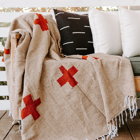 Cozy Trek Light blanket with red cross patterns draped over outdoor seating, perfect for cool evenings and stylish comfort.