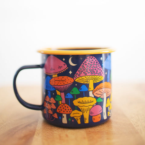 Midnight Mushroom Enamel Mug 16oz with colorful mushroom design by Trek Light on a wooden surface.