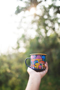 Midnight Mushroom Enamel Mug 16oz held outdoors with colorful mushroom design in the sunlight