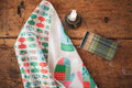 Mittens Kitchen & Tea Towel featuring colorful mitten designs on a wood table with a candle and matchbox.