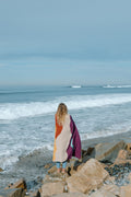 Cozy handwoven Mountain Sunrise Blanket made from recycled materials, perfect for versatility and warmth, by the ocean. By Trek Light.