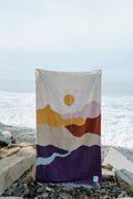 Cozy handwoven Mountain Sunrise blanket made from recycled clothing materials, showcasing beautiful and versatile design by the sea. By Trek Light.
