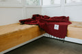 Cozy Napa Blanket in rich red, handwoven from recycled materials by Trek Light. Perfect for naps and eco-conscious relaxation.