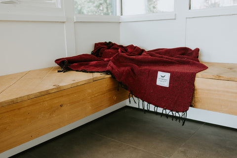 Cozy Napa Blanket in rich red, handwoven from recycled materials by Trek Light. Perfect for naps and eco-conscious relaxation.