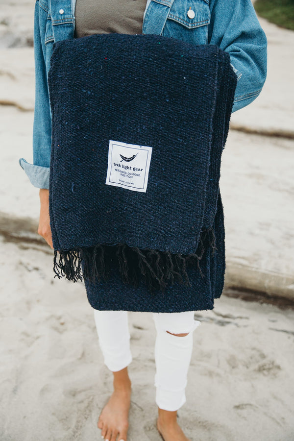 Person holding navy Newport Blanket by Trek Light Gear, ideal for Newport Jazz and Folk Festivals in Rhode Island.