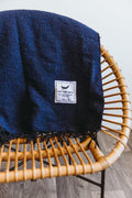 Navy Trek Light Newport Blanket draped over a chair, perfect for Newport Jazz or Folk Festivals. Handwoven elegance.