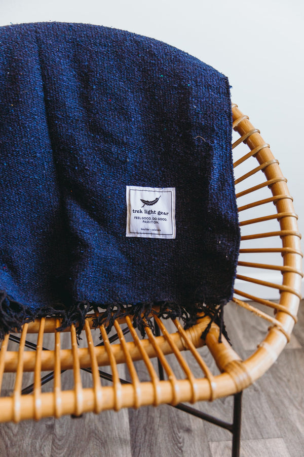 Navy Trek Light Newport Blanket draped over a chair, perfect for Newport Jazz or Folk Festivals. Handwoven elegance.