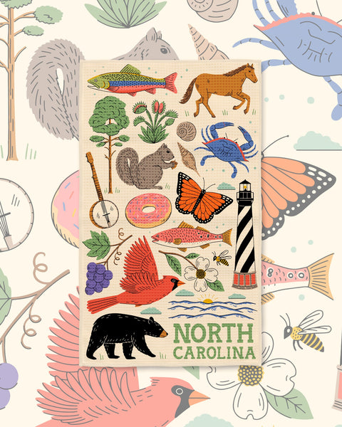 North Carolina Kitchen & Tea Towel with North Carolina icons like a cardinal, black bear, lighthouse and crab on cream