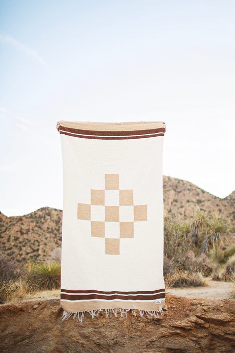 Beautiful handwoven North Star blanket, made from recycled clothing, displayed outdoors. Versatile, cozy, and sustainable. By Trek Light.