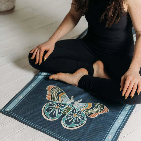 Person sitting on a Trek Light blanket with a colorful butterfly design, showcasing relaxation and comfort.