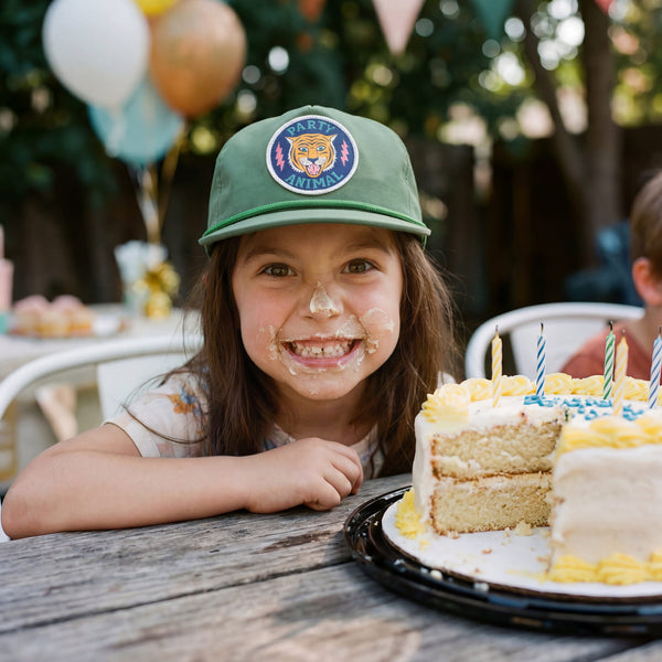 Child wearing a Party Animal Kids Hat, smiling with cake on face, celebrating a birthday party.